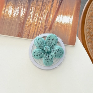 Macro detail of mint green floral phone grip with black speckled texture and clear base