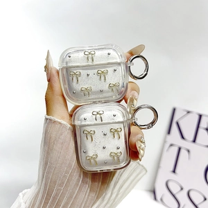 Custodia AirPods glitterata con fiocco dorato 3D e anello in metallo tenuta da modella
