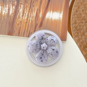 Close-up of a purple floral phone grip holder with black speckle texture and clear base