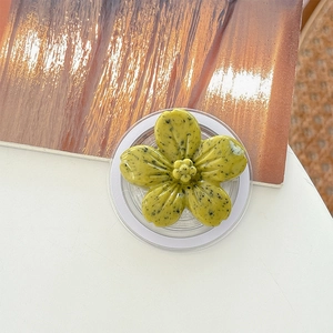 Detail of green flower phone grip with black speckles and transparent base on a desk