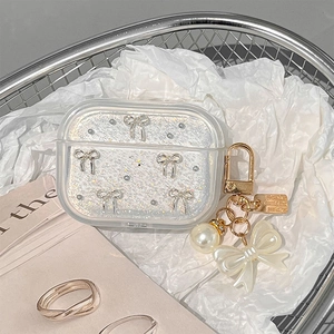 Close-up of glitter AirPods case featuring a silver bow and pearl pendant charm