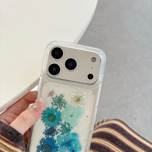 Close-up of clear phone case with blue dried flowers and silver glitter butterfly