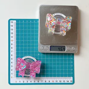 Bow-shaped phone grip showing precise weight and dimensions on a digital scale
