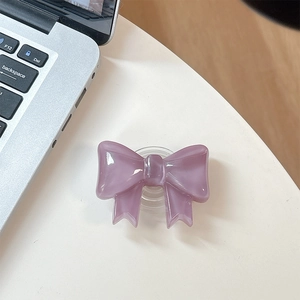 Macro detail of lilac bow phone grip holder on white desk with laptop background