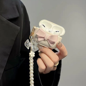 Detailed shot of cream AirPods case with pink bow and elegant pearl chain accessory