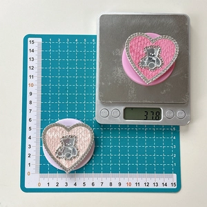 Detail of pink heart phone grips with rhinestone border and teddy bear on weight scale