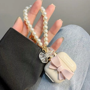 Close-up of AirPods case with pink bow and pearl chain held in hand for a sweet look