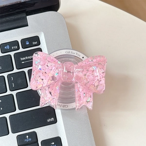 Detailed view of pink heart glitter phone grip attached to a silver laptop