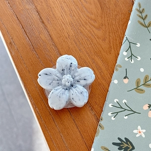 Macro detail of a 3D floral phone socket with grey marble texture on wooden desk