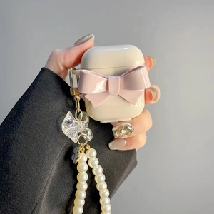 Detail of white AirPods case with a large pink bow and elegant pearl chain strap