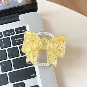 Detail of yellow bow phone socket with heart sequins on a silver laptop background