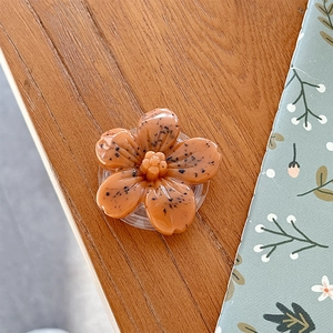 Close-up of a 3D floral phone socket mount with unique black speckled pattern on orange