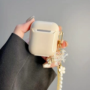 Detail of cream wireless earphone case featuring pearl chain and bow charm accessory