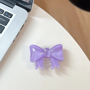 Detail view of purple bow-shaped resin phone grip holder on a white desk