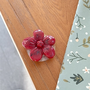 Macro detail of red 3D flower phone grip with dragon fruit texture and clear base