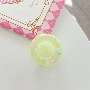 Close-up of a light green translucent button phone grip with colorful cloud dots detail