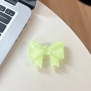 Detail of translucent pastel bow phone socket grip on a clean white desk setup
