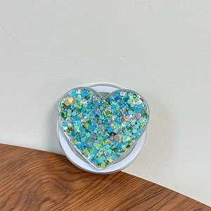 Detail shot of heart-shaped phone grip with multi-colored glitter on wood surface