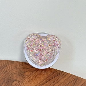 Detail of heart-shaped Griptok with pink glitter and white foldable base on wood surface