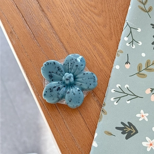 Macro detail of 3D floral phone grip in matte blue finish with ink splatter pattern