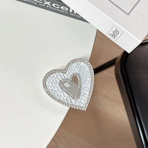 Close-up of heart-shaped rhinestone phone stand with white embossed leather and mirror