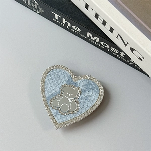 Macro detail of heart-shaped magnetic phone grip with blue snakeskin and rhinestone bear