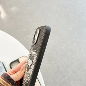 Detailed side view of iPhone case with black lychee leather texture and rhinestone heart bow
