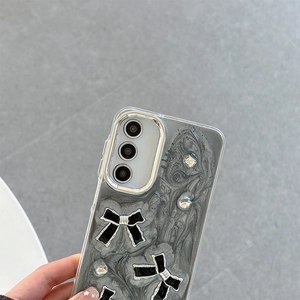 Detail of glitter marble phone case featuring bowknot and rhinestone lens protection