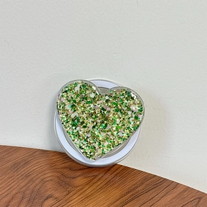 Detail of heart-shaped phone grip with green and gold sequins inside clear acrylic