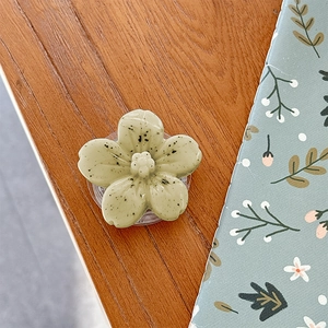 Detail view of a 3D light green flower phone grip holder with marble texture on wooden desk