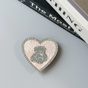 Detail of pink heart-shaped phone grip with leather texture and rhinestone border