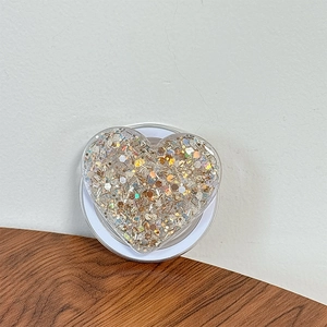 Macro shot of heart-shaped phone grip filled with gold and silver glitter sequins