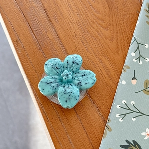 Close-up of a blue 3D flower phone grip with cookie texture on a wooden surface