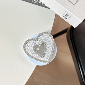 Macro detail of heart-shaped phone grip with rhinestones and white crocodile texture