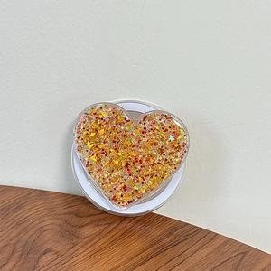 Detail of heart-shaped phone grip with gold glitter and butterfly sequins inside