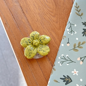 Macro detail of yellow flower phone grip with artistic black spots on a wood desk