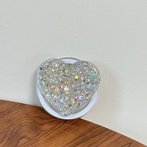 Detailed view of heart-shaped phone grip filled with silver laser sequins and star glitter