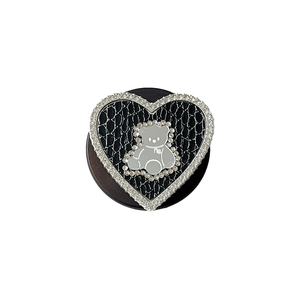 Sparkling rhinestone heart phone socket with a silver bear and lace texture on white background