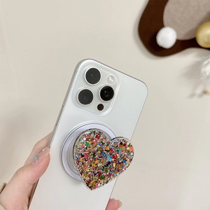 Sparkly heart-shaped phone grip with glitter and sequins held against a smartphone