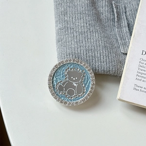 Close-up of a blue bear phone grip with rhinestones on a white background and grey fabric