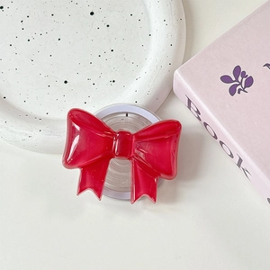 Close-up of a red bow-shaped MagSafe phone grip with transparent retractable base