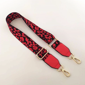 Detail of red leopard print wide bag strap with leather ends and gold metal buckles
