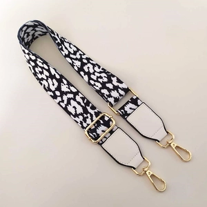 Detail of adjustable leopard print bag strap with white leather ends and gold metal clips
