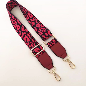 Close-up of red and black leopard print wide bag strap with golden metal swivel hooks