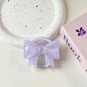 Detail view of a purple bow-shaped magnetic phone grip on a white ceramic tray