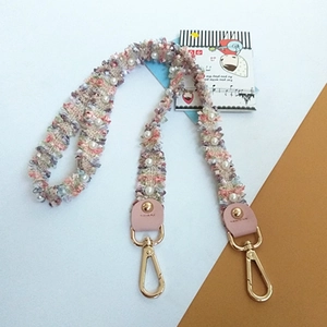 Detail view of woven tweed purse strap with pearl accents and golden metal swivel hooks