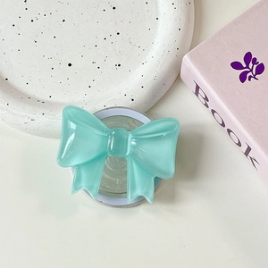 Close-up of mint green bow-shaped MagSafe phone socket on a minimalist desk setting