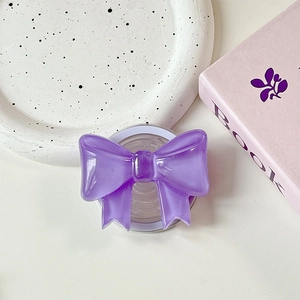 Macro detail of purple resin bow phone grip with collapsible magnetic base on desk