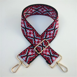 Close-up of wide ethnic embroidery bag strap with golden metal hooks and buckles