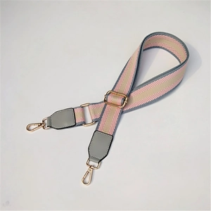 Close-up of pink and grey striped wide canvas bag strap with golden lobster clasps